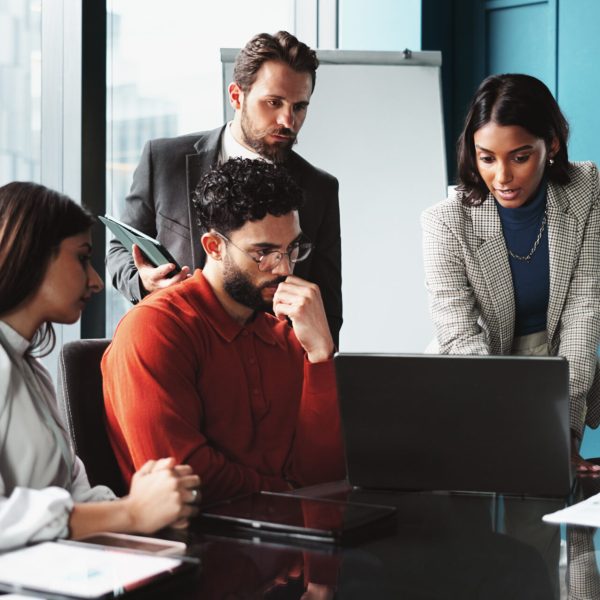 Collaboration, business meeting and group with laptop, office and colleagues with stats for investment. Brainstorming, people and online for accounting in boardroom, corporate and teamwork with data.