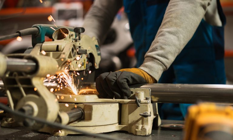Technician worker cutting metal with many sharp sparks. Using equipments to cat iron